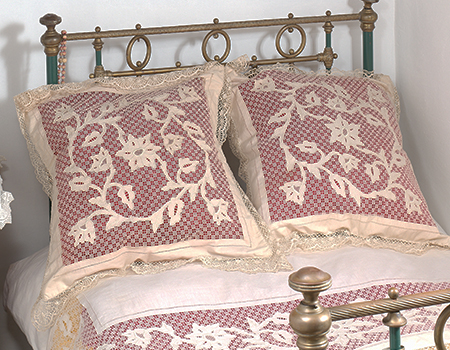 Pormenor de cama tradicional, com almofadões,
lençóis e colcha bordados.
